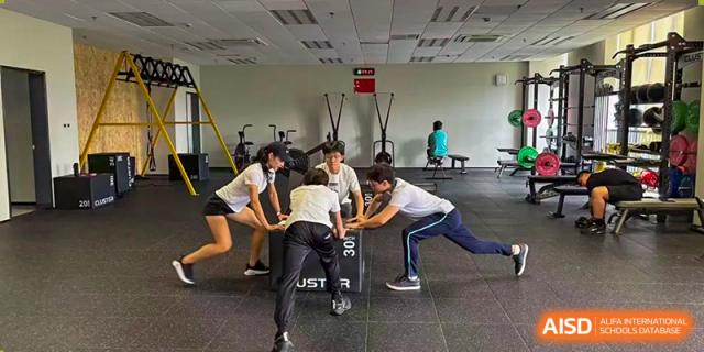 Three Nord Anglia Chinese International School Shanghai students performing a partner plyometric or strength training exercise in the school's gym.