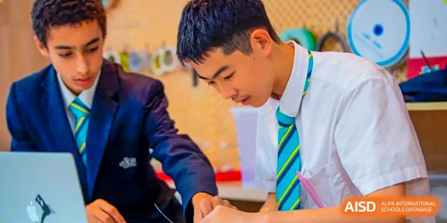 A male student in school uniform with a striped tie intently focused on his work in a classroom at Nord Anglia International School Shanghai, Pudong.