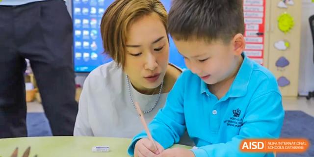 A teacher or mentor helping a young student with writing and schoolwork at Nord Anglia International School Shanghai, Pudong.