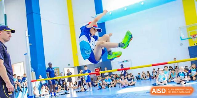 A student jumping high in the air during an indoor sporting activity or gymnastics event at Nord Anglia International School Shanghai, Pudong.