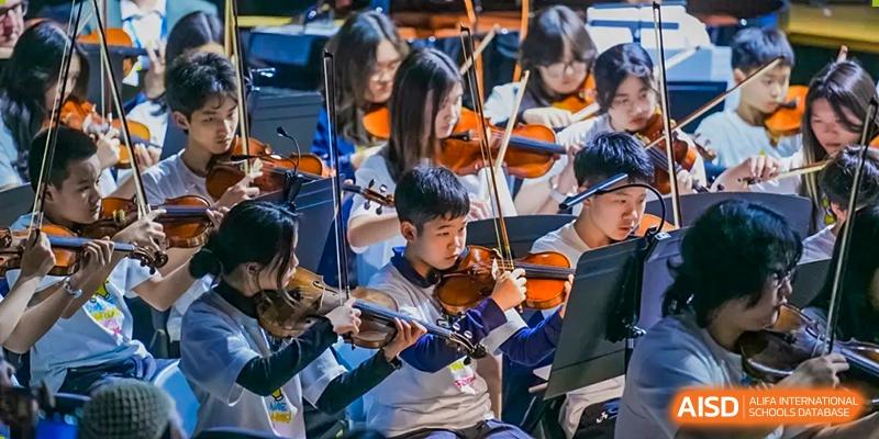 A group of students practicing the violin together during a music class or rehearsal at Nord Anglia International School Shanghai, Pudong.