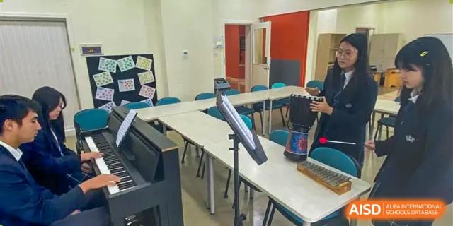 An empty music classroom with tables, chairs, and instrument stands set up at Nord Anglia International School Shanghai, Pudong.
