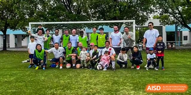 A group of teachers and staff posing for a photo on a grassy field in front of a soccer goal at Nord Anglia International School Shanghai, Pudong.