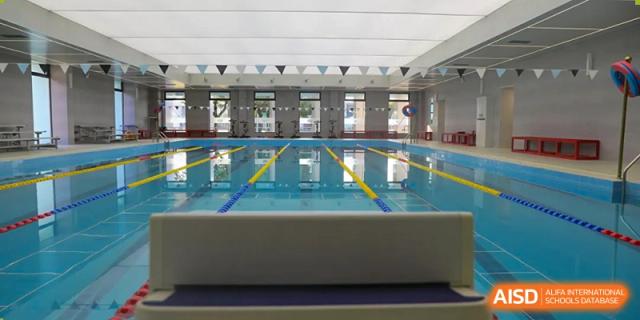 An interior view of the indoor swimming pool with lap lanes and flags at Nord Anglia International School Shanghai, Pudong.