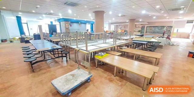 The interior of the bright, spacious school cafeteria with many tables and benches at Nord Anglia International School Shanghai, Pudong.