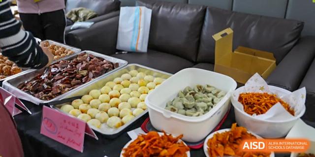 Large catering trays of various prepared foods, including white and gray round items, likely for a school event or meal service at Nord Anglia International School Shanghai, Pudong.