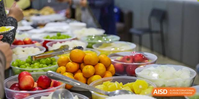 A buffet spread with an abundance of fresh fruits, including oranges and yellow melons, at Nord Anglia International School Shanghai, Pudong.