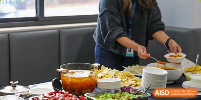 A person serving themselves from a large buffet of healthy food, including salads and bowls of fruit at Nord Anglia International School Shanghai, Pudong.