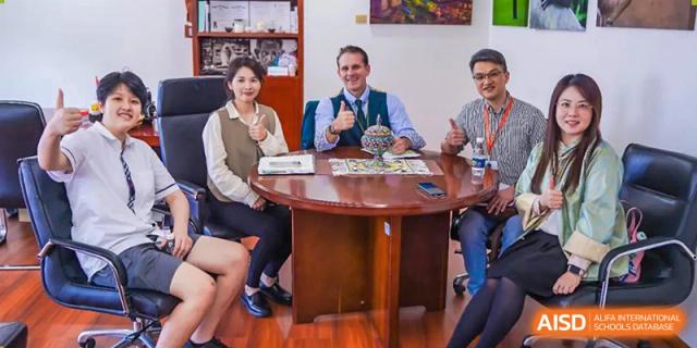 A group of RDF International School staff and teachers sitting around a round table, discussing something in a meeting.