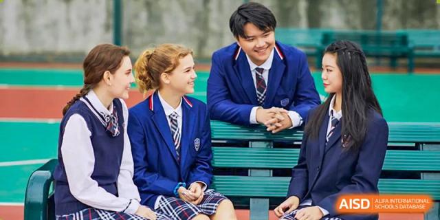 A group of RDF International School students in uniform sitting and talking together on a green bench.