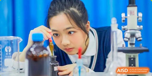 A female RDF International School student looking intently at a chemical reaction or experiment in a science class.