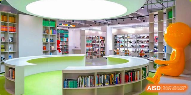 A bright, modern circular library at RDF International School with green and white shelving filled with books.