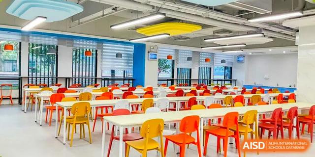 Modern and colorful RDF International School cafeteria with empty tables and bright red, yellow, and orange chairs.