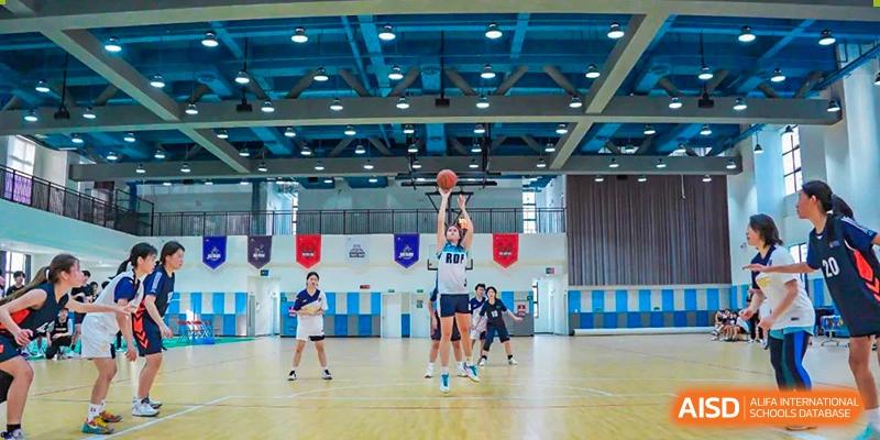 A basketball game or practice taking place in the brightly lit indoor gymnasium at RDF International School.
