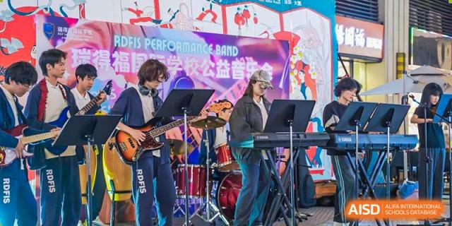 Students performing music with guitars, keyboard, and drums on a stage at RDF International School.