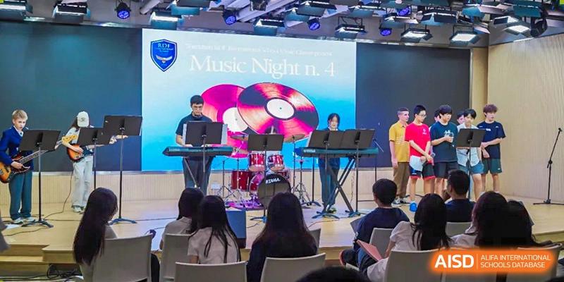 An audience watching a "Music Night" performance on the stage at RDF International School.