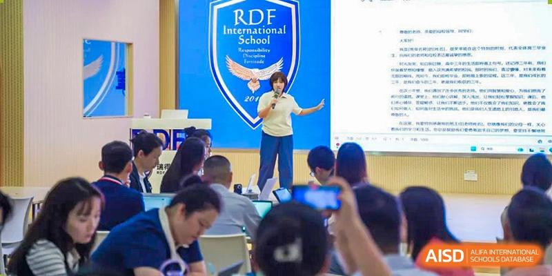 A student making a speech on stage under the RDF International School banner during an event.