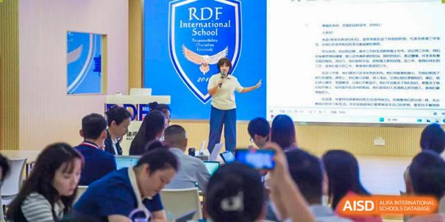 A student making a speech on stage under the RDF International School banner during an event.