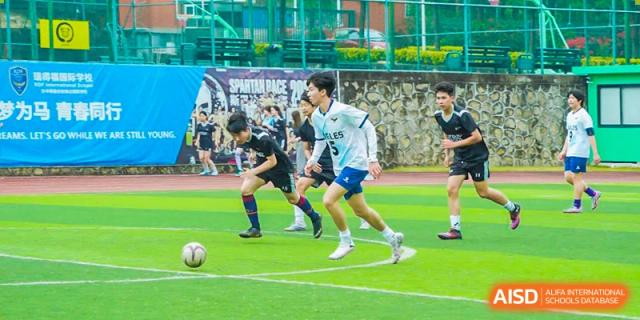 RDF International School students playing soccer in a game, with one player dribbling the ball.