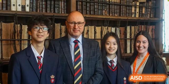 Male teacher/headmaster and female student in uniform posing in a book-lined room at RGS Guildford Nanjing.