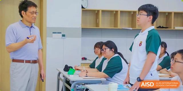 A group of female RGS Guildford Nanjing students in uniform seated at a desk, looking to the side.