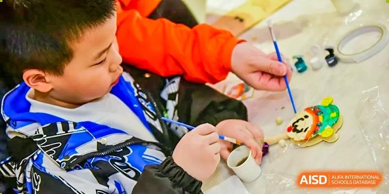 A close-up of a person's hands painting a small object during an activity at RGS Guildford Nanjing.