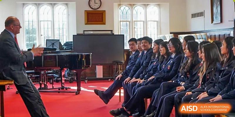 A group of RGS Guildford Nanjing students sitting formally and attentively in a room, possibly a music or lecture hall.