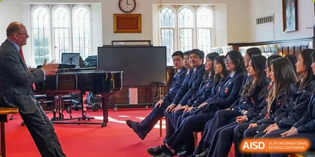 A group of RGS Guildford Nanjing students sitting formally and attentively in a room, possibly a music or lecture hall.