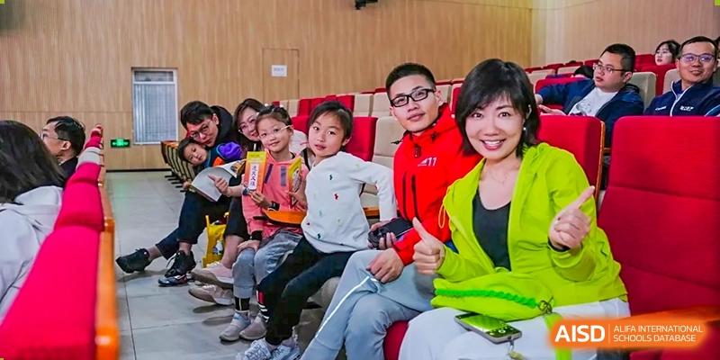 A group of RGS Guildford Nanjing students and teachers sitting together and smiling at a school event.
