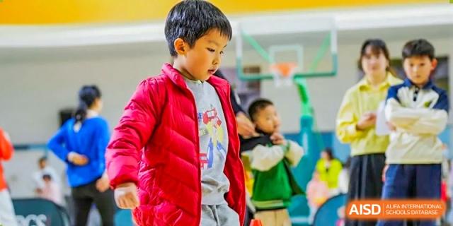 A young boy in a red vest looking focused while participating in an indoor sports activity at RGS Guildford Nanjing.
