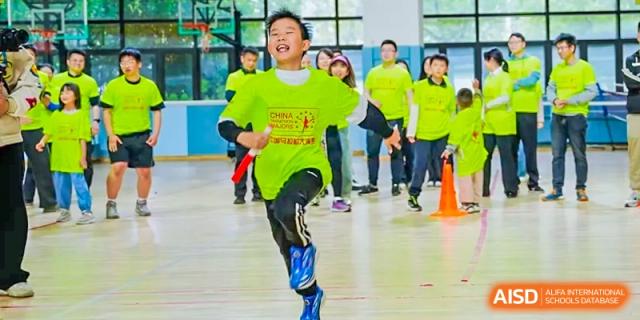 A student in a bright green shirt running during an indoor sports activity at RGS Guildford Nanjing.