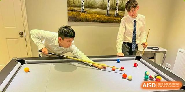 Two RGS Guildford Nanjing students playing a game of pool or billiards indoors.