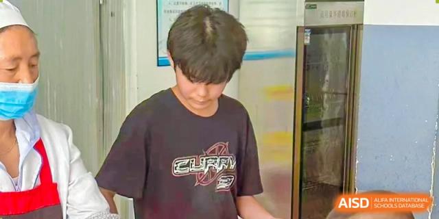 A young male student in a dark t-shirt participating in a cooking activity at RGS Guildford Nanjing.