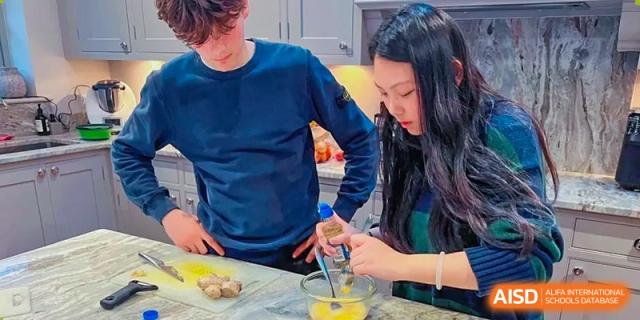 Two people at RGS Guildford Nanjing working together, one whisking ingredients in a bowl.