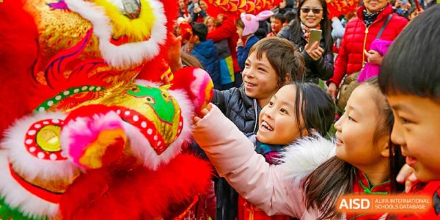 Students enthusiastically interact with a traditional Chinese New Year lion dance during a cultural celebration at Shanghai Community International School.