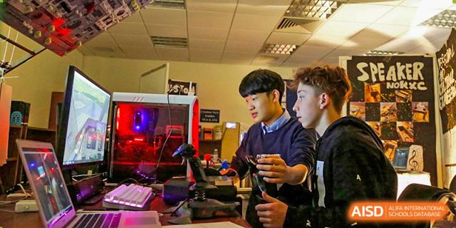 A male student works intently on an engineering or coding project using specialized equipment in a lab at Shanghai Community International School.