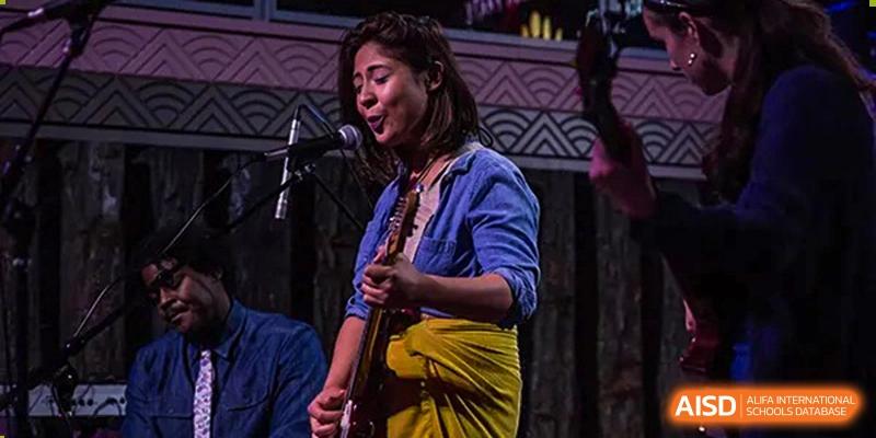 A female student plays an electric guitar and sings into a microphone during a live performance at Shanghai Community International School.