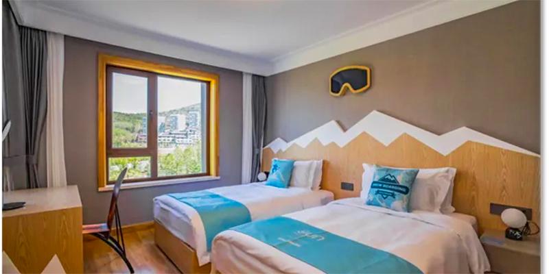 A well-appointed hotel or dormitory room with two beds and a modern mountain-themed wall decoration, potentially used for school trips or student housing at Shanghai Community International School.