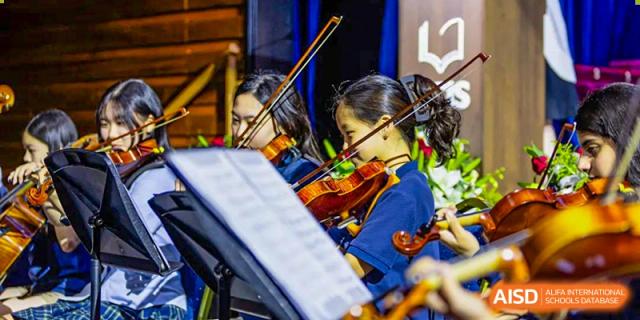 Two students playing the violin and viola, concentrating on their sheet music during an orchestra performance at Shanghai Community International School.