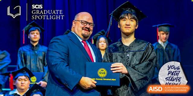 A male graduate in a cap and gown receives his diploma from a school administrator during the commencement ceremony at Shanghai Community International School.