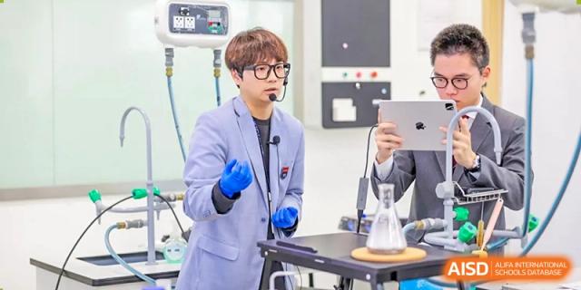 A teacher or student, wearing blue gloves, demonstrates a scientific experiment using glassware and a burner in a lab at Shanghai DTD Academy.