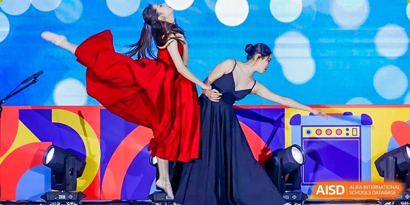 Two female performers in formal dresses dance gracefully on a brightly lit stage during an event at Shanghai DTD Academy.