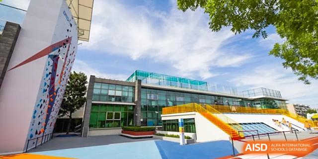 An exterior view of a modern, brightly colored school building and outdoor play area under a sunny sky at Shanghai DTD Academy.