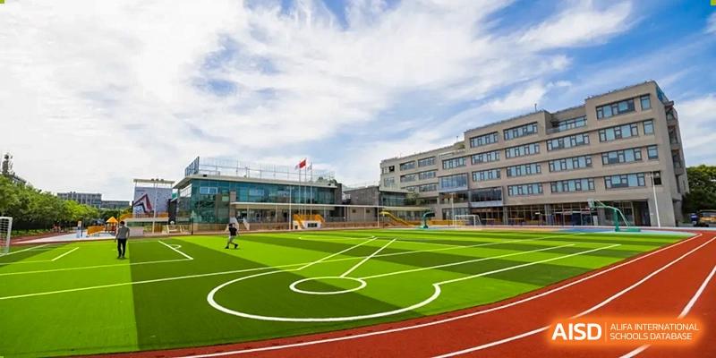 An aerial view of the school's outdoor multi-purpose sports court/field with white markings and surrounding buildings at Shanghai DTD Academy.