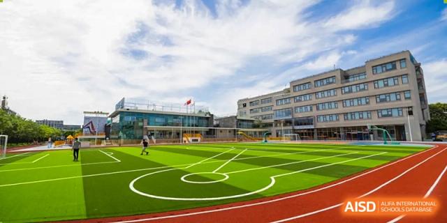 An aerial view of the school's outdoor multi-purpose sports court/field with white markings and surrounding buildings at Shanghai DTD Academy.