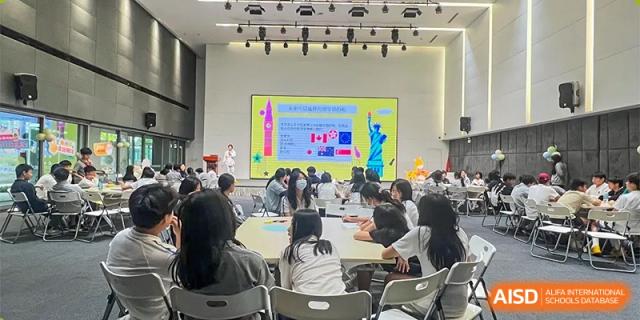 Students are seated and engaged in a conference room, looking toward a large screen displaying information and flags during an event at Shanghai DTD Academy.