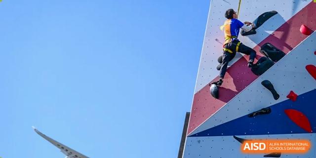 A view of a colorful, angled outdoor rock climbing wall extending up against a clear blue sky at Shanghai DTD Academy.
