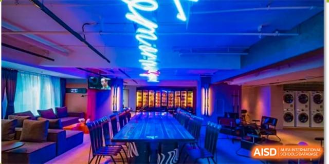 A modern, dimly lit dining or event space with a long table, featuring a bright blue neon sign on the wall at Shanghai DTD Academy.