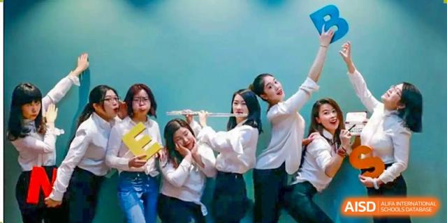 Female students from Shanghai New Epoch Bilingual School posing together, one holding a flute, during a music or performance activity.