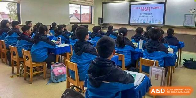 Students from Shanghai New Epoch Bilingual School seated in a classroom, viewed from behind, paying attention to the front of the room.